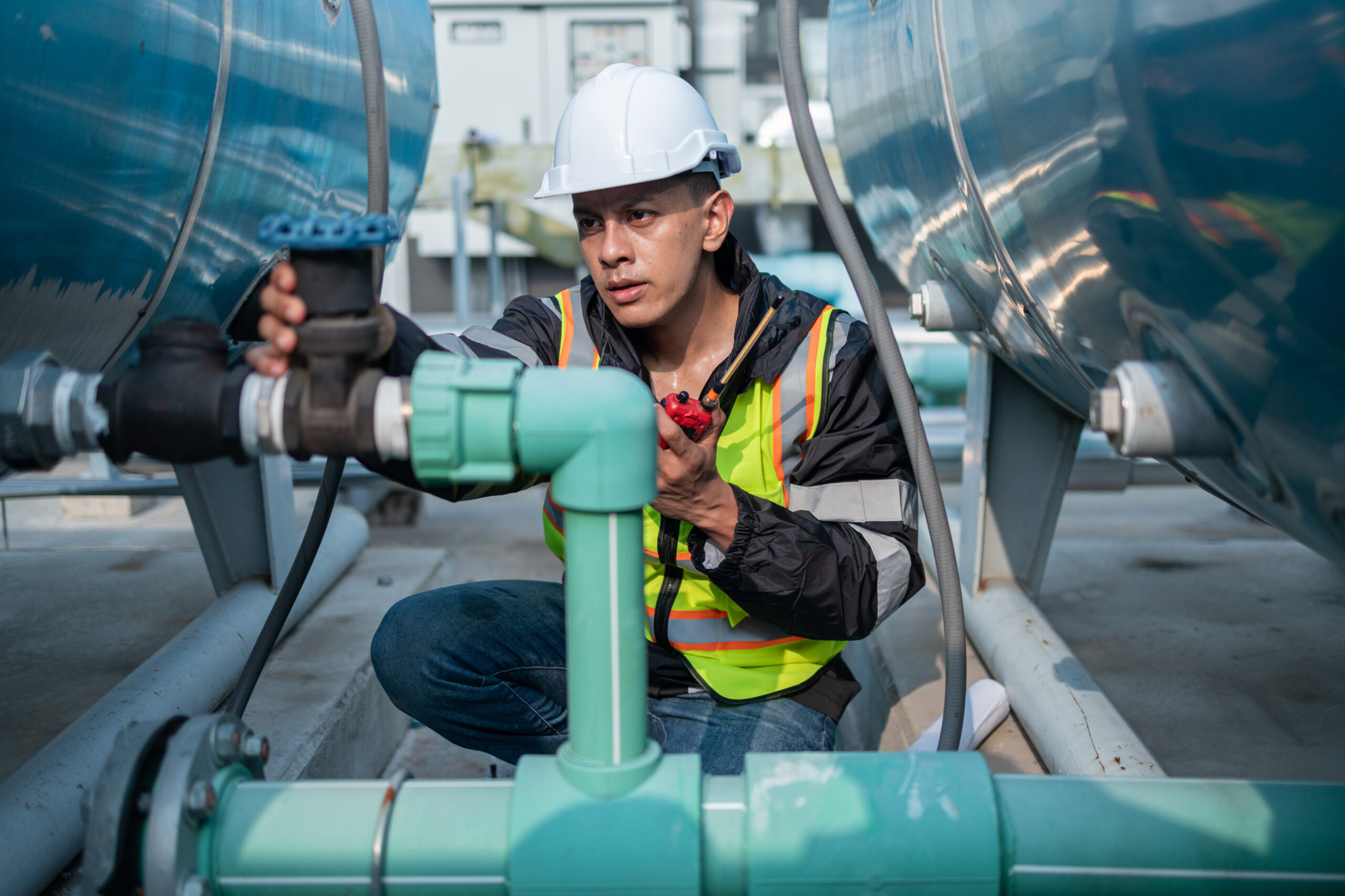 Focused industrial engineer using a calibration tool to check equipment at a manufacturing plant, ensuring operational efficiency.