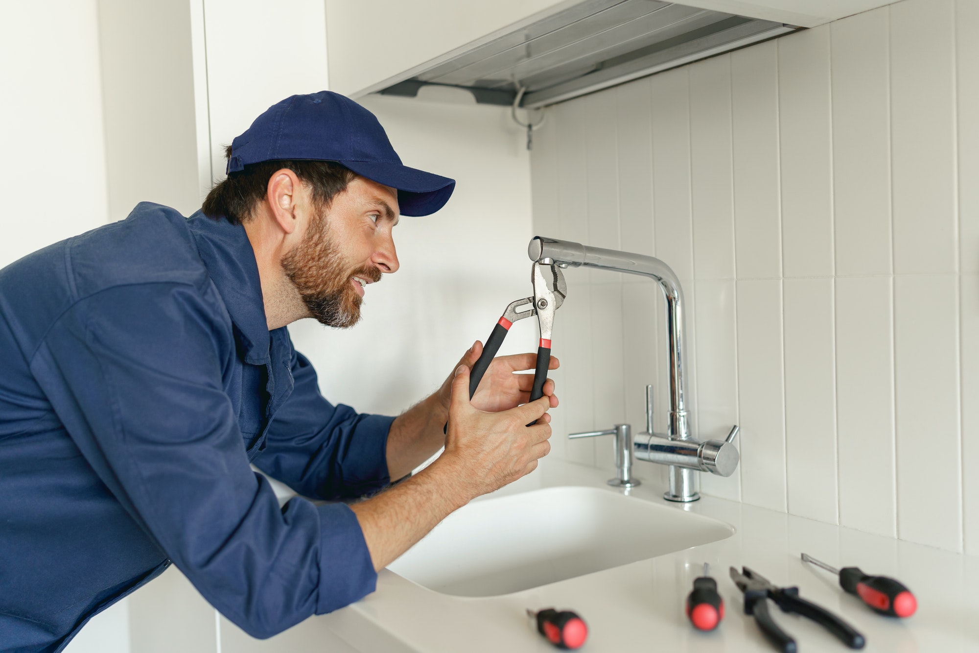 professional-plumber-in-blue-uniform-fixing-broken-water-tap-in-kitchen-repair-service-concept.jpg