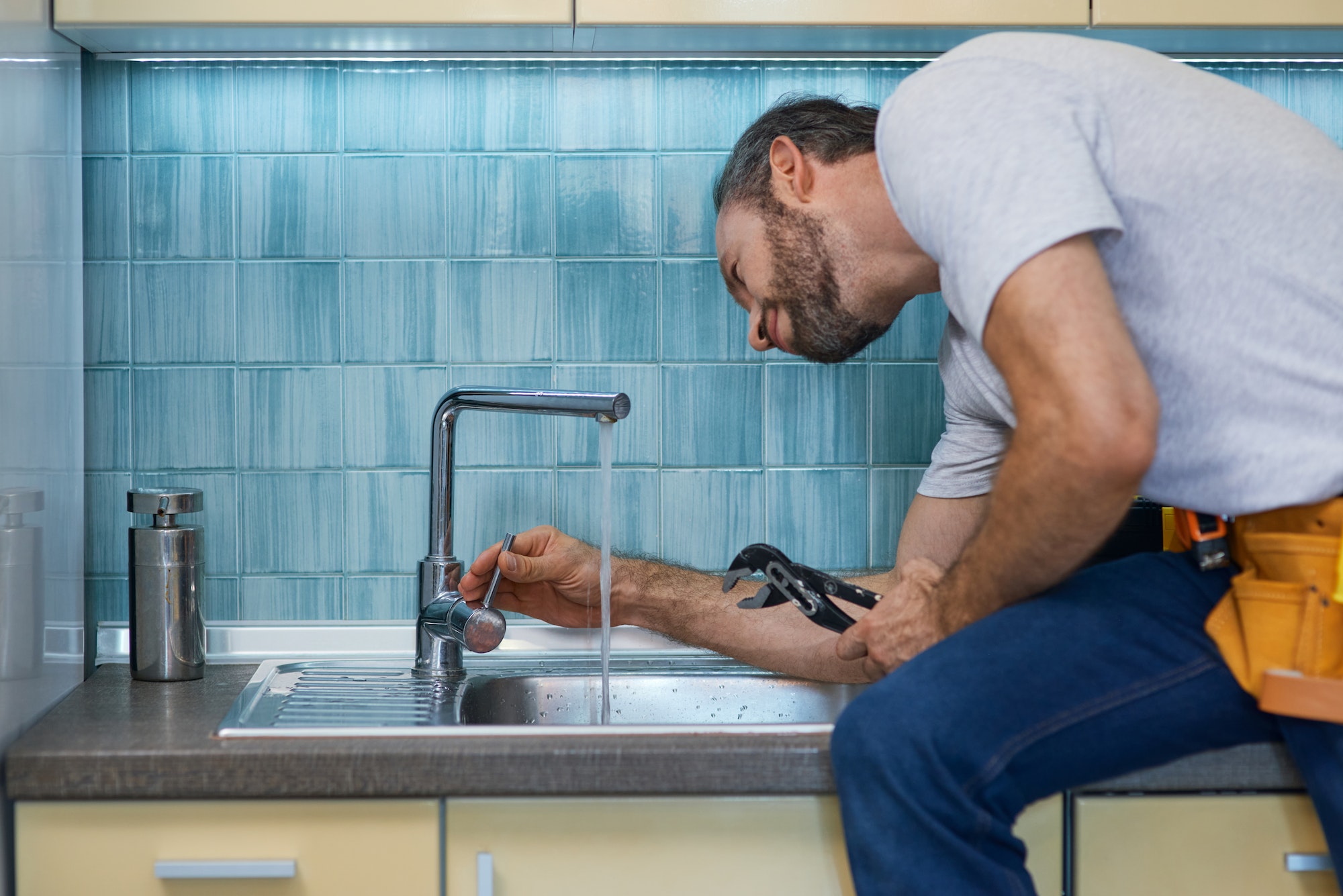 professional-plumber-looking-concentrated-using-pipe-wrench-while-examining-and-fixing-faucet-in.jpg